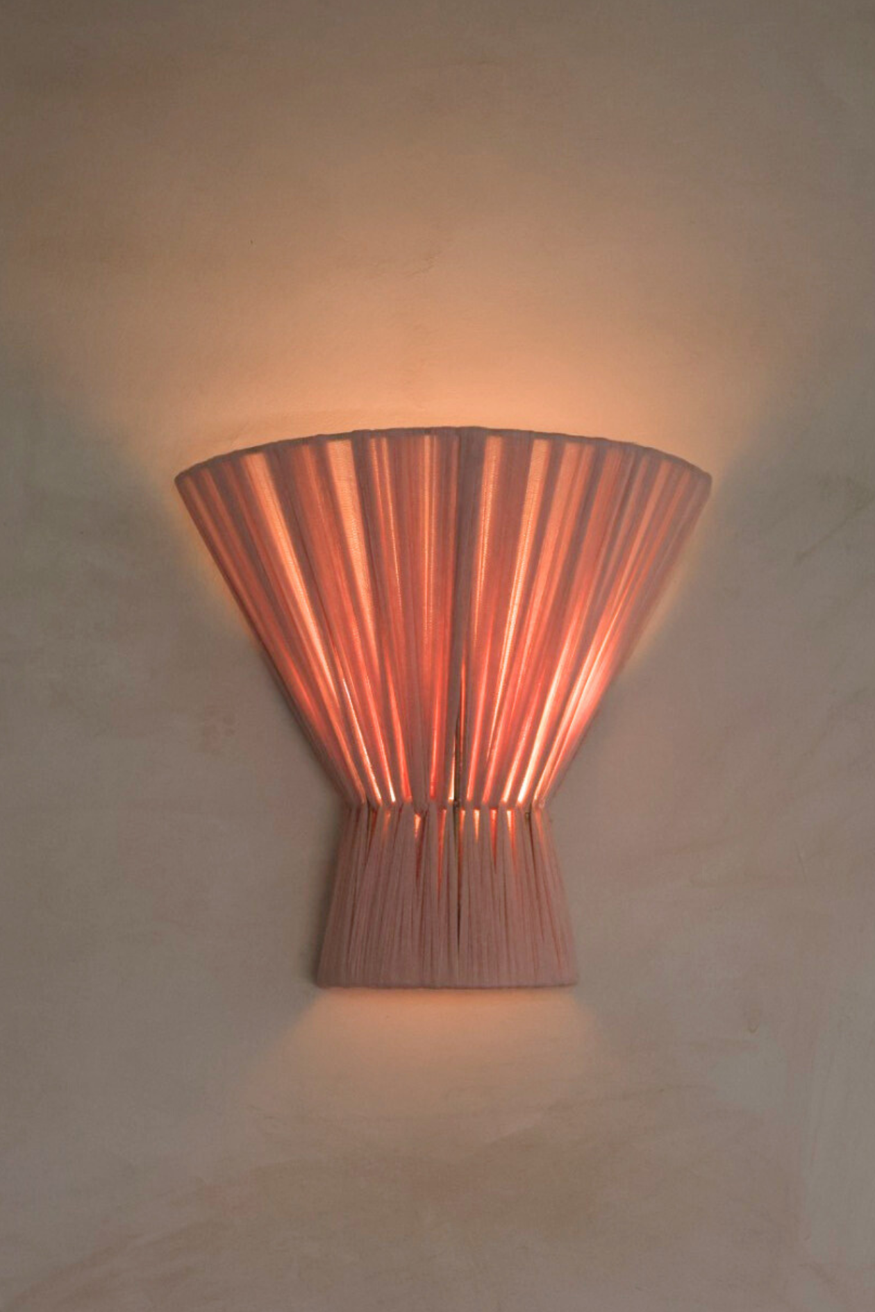 Blush pink wall sconce on a beige wall
