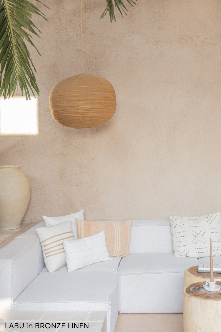 A bronze linen pendant light shade with a rattan frame, hanging and displaying a textured surface.