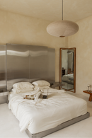 Modern bedroom with a large bed, mirror, and minimal decor.