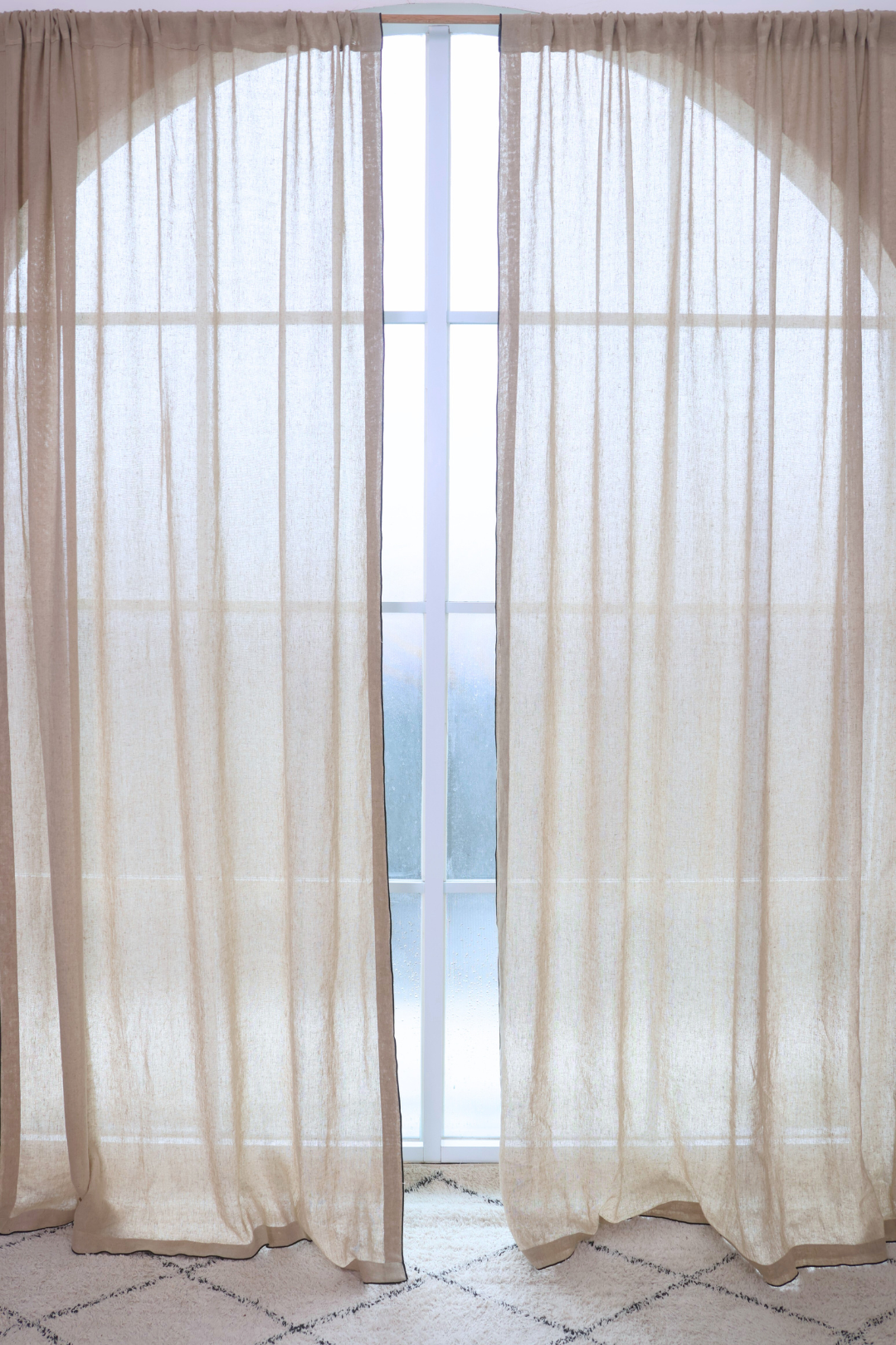 Sheer beige curtains with a blurred window view in the background